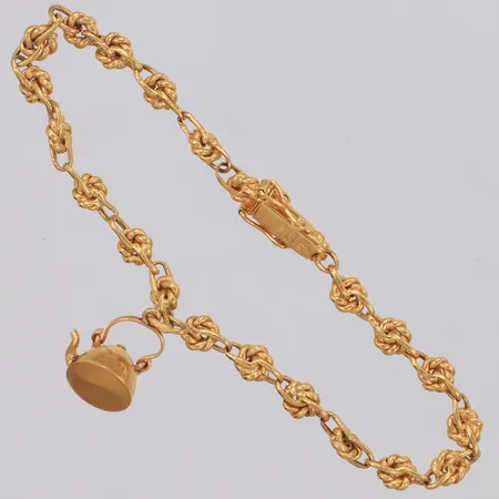 Armband med en berlock i form av kaffepanna, längd 17,5cm, bredd 2,3mm, lätta bucklor, importstämplat 18K Vikt: 5,6 g