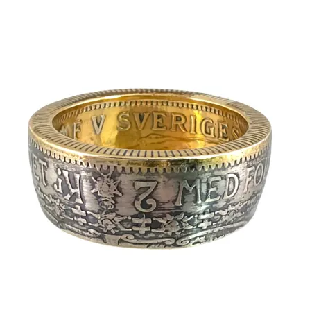 Myntring herrmodell silver 800/1000, hantverksmässigt tillverkad/driven från ett svenskt silvermynt (2 krona 1928), stl:20,5 mm, bredd 9,4 mm, förgylld inuti liksom på kantrand, fint skick, förefaller sparsamt använd, dessa ringar med förgylld yta brukar kosta från omkring 2000 kr och uppåt beroende på tillverkare och kvalitet Vikt: 12,5 g