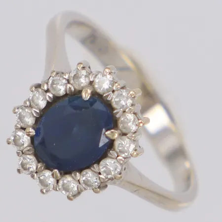 Ring med blå sten samt diamanter 14x 0,02ct, 0,30ctv enligt gravyr, vitguld, stl:17¼, bredd 13mm, kraftigt slitage på den blå stenen, 18K Vikt: 3,9 g