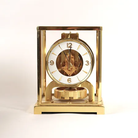 Bordsur Jaeger-LeCoultre Atmos, förgylld mässing och glas, höjd 22cm, längd 16cm, bredd 12cm, snr 281747, framlucka i glas har lossnat, ej funktionstestad. OBS! Skickas ej.  Specialfrakt, kontakta pantbankskontoret för mer information.