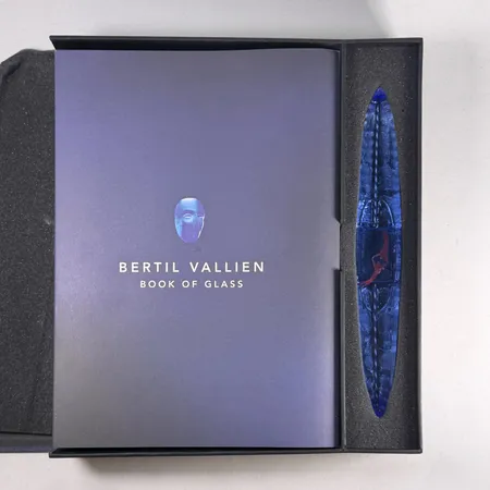 Bertil Vallien Book of Glass: Vessel Edition 2020, bok samt glasskulptur, i box med teckning numrerad 349/500, Book of Glass 2020 (Kosta Förlag), text Staffan Bengtsson, glasskulptur blåtonat glas 28cm, signerad i botten 7520149 Kosta Boda Lim.ed 500 2020 samt signerad B. Vallien på ovansidan, bok med smärre bruksslitage, mycket sliten box Skickas med postpaket.