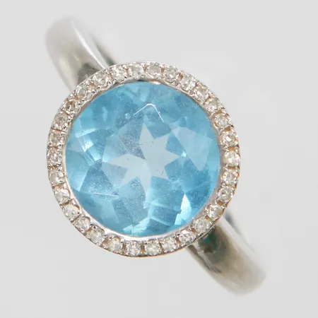 Ring med en blå topas Øca.9mm samt diamanter 30 x ca.0,003ct, 8/8-slipade, stl:16, bredd: 1,6-10,8mm, GHA, litet nagg på topasen, vitguld, 18K Vikt: 4,7 g
