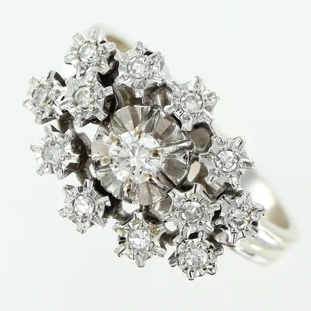 Ring stl:17½ diamanter 1xca0,11ct briljantslipad, 12xca0,01ct 8/8-slipade, bredd på skena 2mm, ovandel 11,5x15mm, vitguld 18K Vikt: 4,6 g