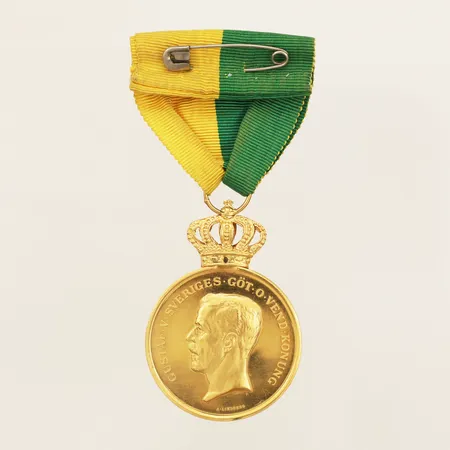Förtjänstmedalj Gustaf V Sveriges Göt O Vend Konung, Af Kungl Patriotiska Sällskapet för lång och trogen tjänst, Ø35mm gravyr defekt etui medalj 23K bandfästet 18K bruttovikt 30,8g Vikt: 30,8 g