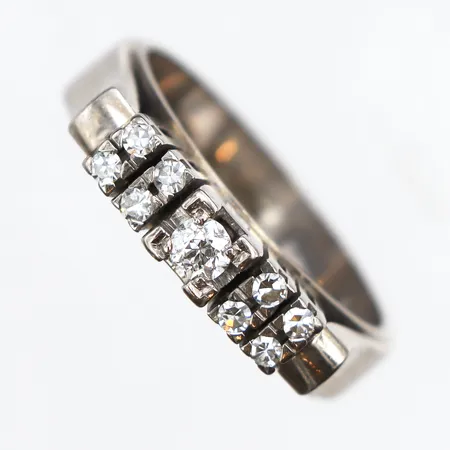 Ring med 9 diamanter 0,25ctv enligt gravyr, stl:17, bredd: ca 5,3mm, vitguld 18K. Vikt: 8,1 g