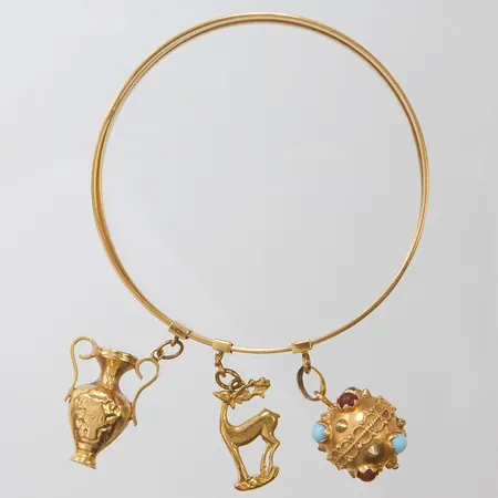 3 Armringar ihopsatta till en, innermått Ø66mm, bredd: 2,5mm/st, tre integrerade berlocker varav en med stenar, mindre bucklor samt repor, 18K, bruttovikt 35,0g Vikt: 35 g