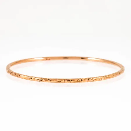 Armring med utvändig mönstergravyr. Den är Ø 65 mm, 2,5 mm bred och väger 14,2g. Håller 16K i densitetstest.