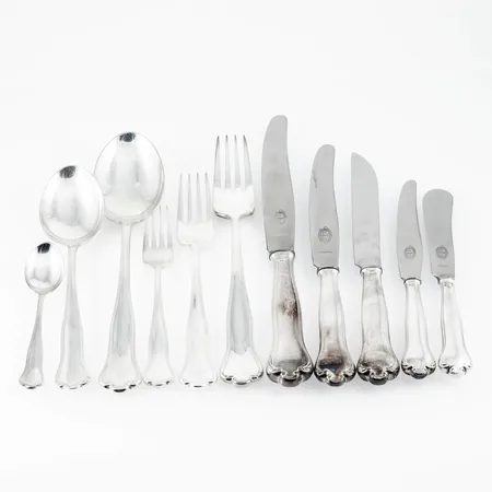 Parti silver (830/1000) modell Kungsholm: 12 bordsgafflar (175 mm), 4 matgafflar (210 mm), 12 smörgåsgafflar (145 mm), 11 bordsskedar (177 mm), 1 matsked (208 mm), 6 kaffeskedar (112 mm), 12 smörgåsknivar med rostfria blad (175 mm), 12 bordsknivar med rostfria blad (213 m), 4 matknivar med rostfria blad(244 mm), 1 ostkniv med rostfritt blad (205 mm), 6 smörknivar med rostfria blad (165 mm). de fyllda delarna med rostfria blad väger 1866g bto. Totalvikt ca 4268g. Hallbergs från 1950-60-talen. Bruksskick, repor, monogramgravyr på alla delar. Skickas med postpaket.
