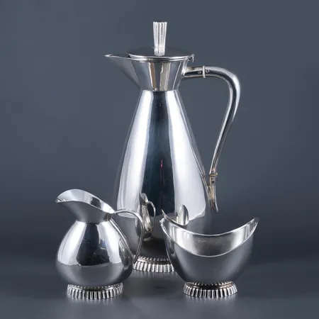 Kaffeservis i silver (925/1000): kanna ca 23 cm hög, gräddkanna ca 9 cm, sockerskål ca 7 cm. Stämplade STERLING 925 och svenska importstämplar. De väger 448g tillsammans.