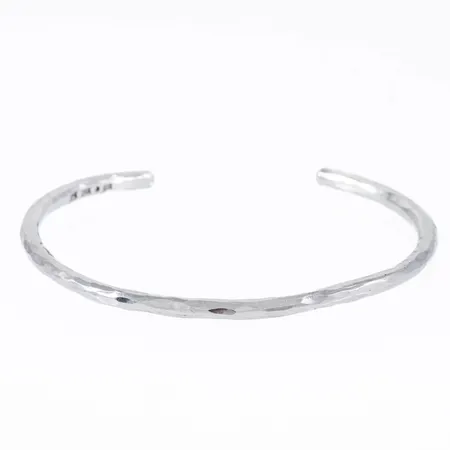 Armring i silver (925/1000) med hamrad yta. Innermått 18 cm inkl. öppning 27,5 mm. Den är 3,5 mm bred och väger 13,3g. Stämplad E11 (2003), GIU (Guldsmedjan i Umeå AB, 925.