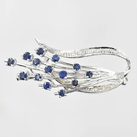 Brosch med diamanter 0,09ctv och safirer ca 0,50 ctv bredd 45 mm, höjd 20 mm vitguld, 18K. Vikt: 8,6 g