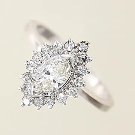 Ring med diamant ca 0,50ct marquiseslipad troligen laserbehandlad, samt 16 x ca 0,02ct åttkantslipade, fåtal av de mindre diamanterna troligen syntetiska, stl 16 bredd 2-14mm, en defekt klo, vit metall