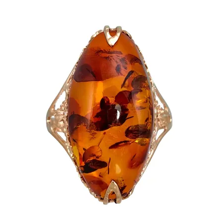Ring i 14K guld med större Bärnsten, dekorerad fattning, stl:19¼ mm, bärnstenens storlek 12,5 x 26 mm, bärnstenens tjocklek/höjd 9,5 mm, ringens bredd 2 - 26,5 mm, oidentifierad tillverkarstämpel, fint skick, bärnsten utan anmärkning Vikt: 5,2 g