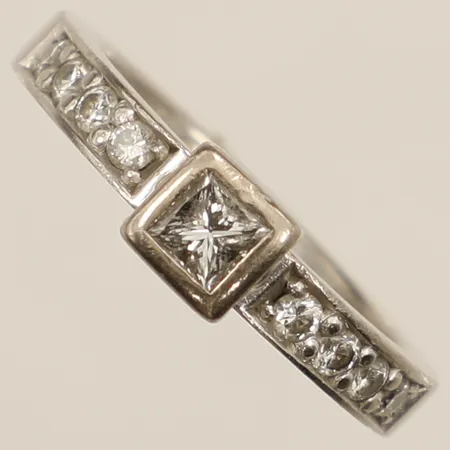 Ring med diamanter 8xca0,03ct samt en diamant prinsesslipad diamant 1xca0,24ct, totalt 0,49ct enligt gravyr stl:16 bredd 5mm, gravyr, Schalin vitguld 18K Vikt: 5 g