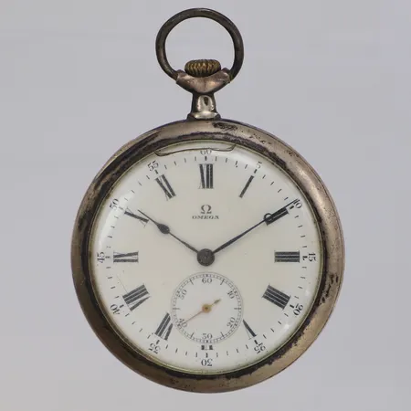 Fickur Omega Ø 50mm, serienummer 4640785, innerboett i metall, tidigt 1900-tal, skadat glas, bucklig bakboett, 900/1000 silver