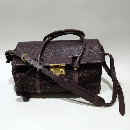 Handväska Louis Vuitton bourdeaux-färgad jaquardvävd och monogrampräglad väska. Lock och remmar i kalvskinnsläder guldfärgade metalldetaljer, spänne märkt "LOUIS VUITTON PARIS". Limiterad edition 2010 fodrad med svart tyg en innerficka. Mått ca 36 x 14 x 24 cm, lås och nyckel finns