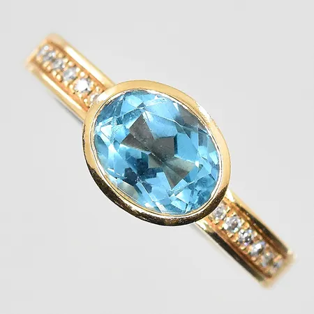 Ring med diamanter 12x0,01ct och blå topas, stl 17½, bredd 3-8mm, 18K. Vikt: 7,6 g