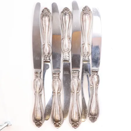 7 Knivar, längd 25,5cm, bredd 13-26mm, GAB (Guldsmedsaktiebolaget I Stockholm) år 1955, blad i rostfritt stål, handtag i silver, 830/1000 silver Vikt: 547 g