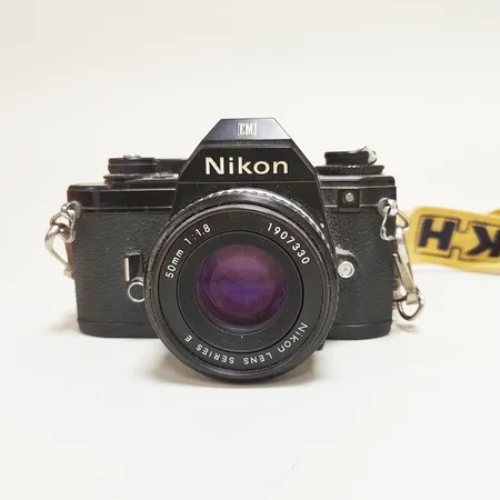 Analog kamera Nikon EM, snr: 6948802, i behov av rengöring, objektiv Nikon 50mm f1:1,8, snr: 1907330, axelband,  kameraväska Nikon läder Vikt: 0 g