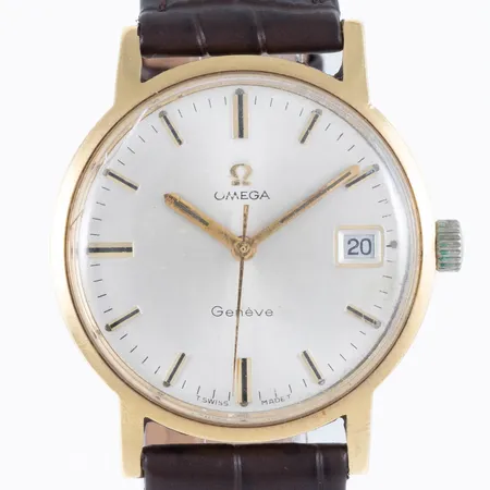 Herrur Omega Genéve i 18K guld med brunt läderband. Boett Ø 34,5 mm, manuell, datumvisare, repor och spricka på originalglas, guldplätering bortnött från krona, gravyr. Bruttovikt: 41,0g.  