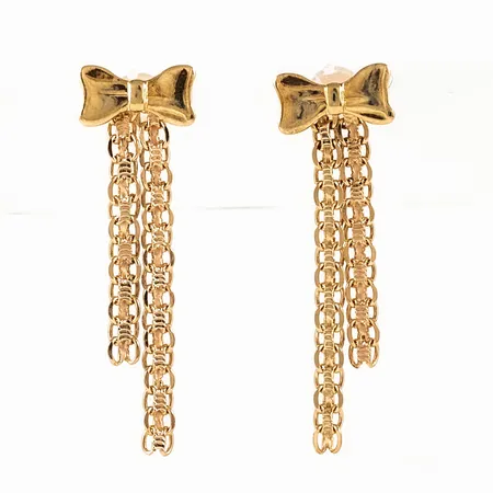 Örhängen i 18K guld: Rosett med hängande dekor. De är 8 mm breda, 26 mm långa och väger 1,6g. Snurrebussar saknas, men nya i plast medföljer. 