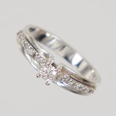 Ring med diamanter 1x ca 0,15ct, 14x ca 0,01ct, stl 18, bredd 3,2-4,6mm, vitguld 18K Vikt: 3,8 g