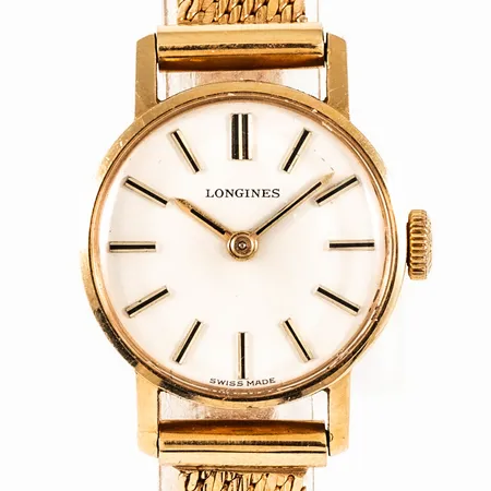 Damur Longines i 18K guld med urband i 18K. Boett Ø 19 mm, manuell, plexiglas. Total längd 17/17,5 cm. Fungerade vid testtillfälle. Ett svagt veck i bandet, annars i fint skick. Bruttovikt: 25,7g. 