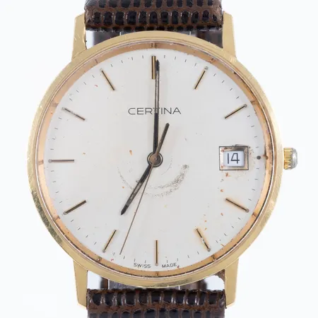 Herrur Certina i 18K guld med brunt (defekt) läderband. Boett Ø 33,5 mm, datumvisare, safirglas, quartz, gravyr, fläckar/märken på urtavla, defekt/lös krona, går ej att ställa. Går ej - Batteribyte krävs? Bruttovikt: 28,2g. 