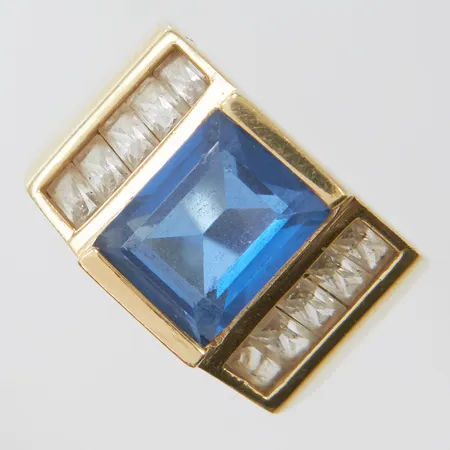 Ring med blå syntetisk spinell samt vita stenar, stl16¾, bredd 5,5-12mm, repig skeva samt stenar, 14K, bruttovikt: 7,6g.