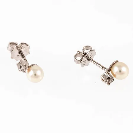 Örhängen i 18K vitguld med två saltvattensodlade gräddvita pärlor Ø 4,5 mm och 2 x c:a 0,02ct briljantslipade diamanter. De är 2 - 4,5 mm breda, 7 mm långa och väger 1,4g. Stämplade HS (Hans Strömdahl, Stockholm), 18K och kattfot.