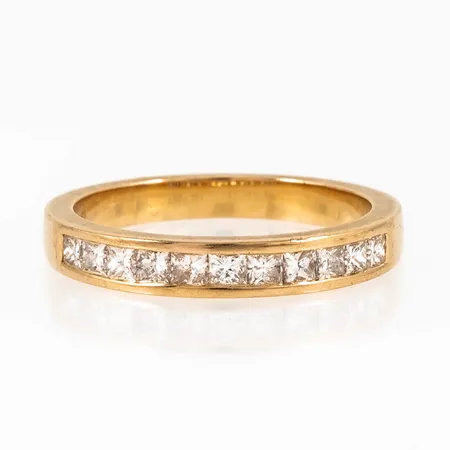 Ring i 18K guld med 11 x 0,045ct princesslipade diamanter i kanalfattning. Den är i storlek 17¼, är 2,5 - 3 mm bred och väger 3,8g. Stenstorlek 0,50ct ingraverad. Stämplad GHA (Guldfynd), 750. 