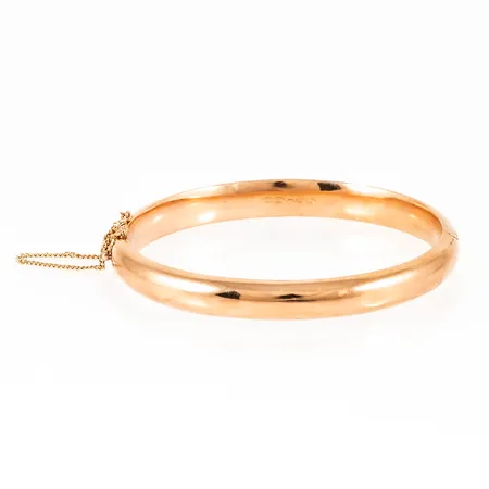 Armring i 14K guld. Innermått 19 cm, bredd 8,5 mm, vikt 14,5g. Öppningsbar, säkerhetskedja, gravyr, svag buckla. Finska stämplar. 