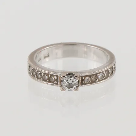 Ring med diamanter 1 x ca. 0,20 + 12 x ca. 0,02ct, Ø16¾, bredd: 3,5mm, vitguld, 18K, 5,5g.