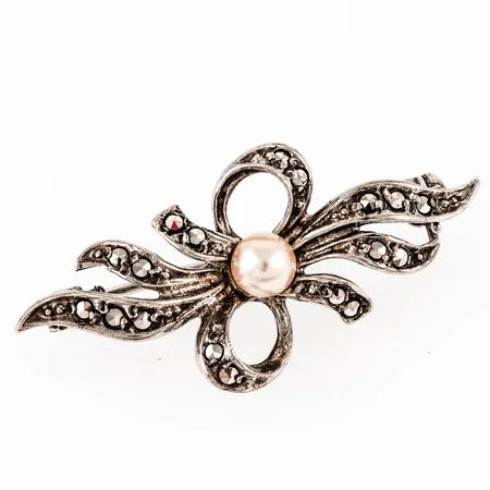 Brosch i silver (925/1000) med odlad vit pärla Ø 4,5 mm och markasiter. Det är 34,5 x 16,5 mm och väger 3,5g. 