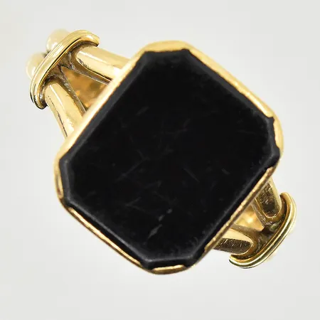 Klackring med onyxplatta, stl 21¾, bredd 5-16 mm, repig sten, gravyr, 18K. Vikt: 8,2 g