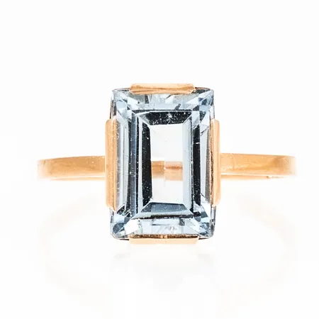Ring i 18K guld med en ljusblå sten (sannolikt syntetisk spinell) 11,5 x 8 mm. Den är i storlek 18¼, är 1,5 - 12 mm bred och väger 3,2g. Stämplad X8 (1948), GVH (Guldvaruhuset AB, Stockholm), 18K och kattfot. 