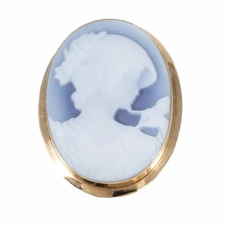 Camébrosch / Hänge i 18K guld. Syntetisk camé. Det är 25 mm brett, 32,5 mm långt exkl. infällbar ögla och väger 5,7g. Ojämnheter på kant runt camé.