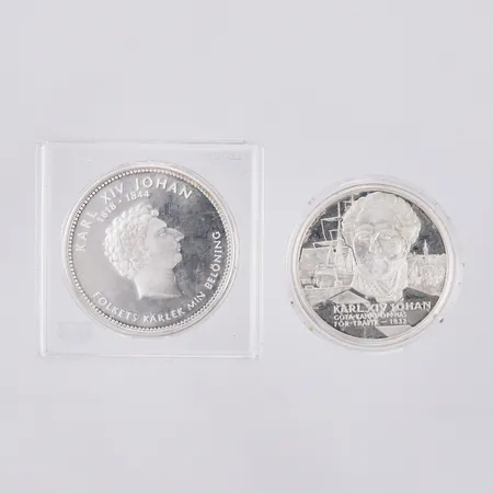 Mynt "Konungaätten Bernadotte Karl XIV Johan Folkets kärlek min belöning", 1 mynt "Kungariket Sverige Karl XIV Johan", båda mynt med plastetui varav 1 etui trasigt, silver 925/1000, vikt: 52,9g Vikt: 52,8 g