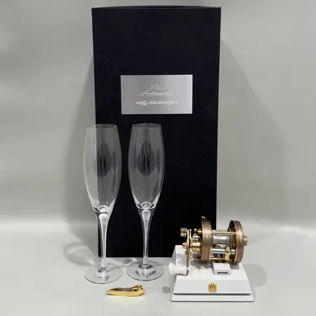 Fiskerulle Abu Ambassadeur 5500CS, Champagne edition, förgylld, Abu Garcia, 1952-2012, numrerad 277/500, med träsockel, Orrefors Intermezzo, två stycken champagneglas, höjd ca 24cm, manual samt förgylld slipsnål, originalkartong med slitage