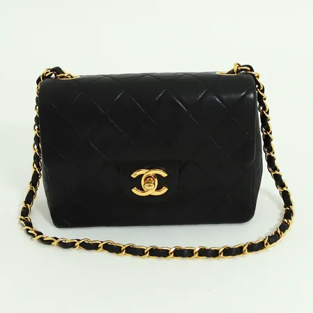 Väska Chanel Flap Bag mini 1991-1994, svart kalvläder med beslag i guldfärgad metall, foder i rött läder, invändigt två fack varav en med dragkedja, certifikatkort, numrerad, märkt Chanel made in France, ca 17,5 x 13 x 6 cm, bottenhörn något slitna, överlag smärre bruksskick med enstaka små repor. 