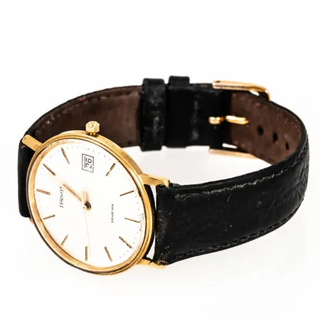 Herrur Tissot Seastar i 18K guld med svart läderband. Boett Ø 33,5 mm, datum, quartz, repigt glas, defekt krona, går ej att ställa, gravyr. Går ej - Batteribyte krävs?Bruttovikt: 29,8g.