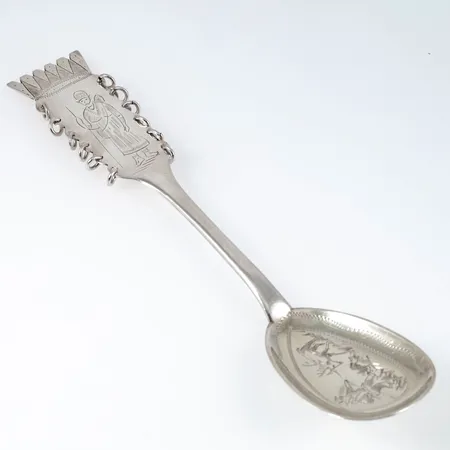 Uppläggningssked i silver med handgraverat samemotiv. Den är 207 mm lång och väger 55,0g. Tillverkad 1968 av CO Persson i Haparanda. Datumgravyr på baksidan. Repor / nött förgyllning.