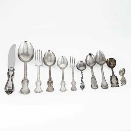 Parti graverat silver (830/1000): 12 bordsknivar Olga, längd 200 mm Bruttovikt: 650g (c:a nettovikt 130g), 4 bordsskedar Olga, längd 180 mm, 6 smörgåsgafflar Olga, längd 150 mm, 5 teskedar Olga, längd 140 mm, 7 kaffeskedar Olga, längd 123 mm, 2 assiettgafflar, längd 122 mm. 10 skedar blandade modeller. 2 defekta broscher Lappsked graverad Lycksele. Vikt exkl. knivar: 696g.