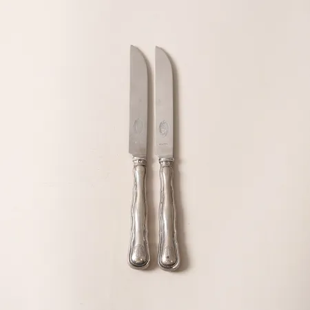 Två Knivar, modell Hallbergs Chippendale, längd: 21cm, monogram, blad i rostfritt stål, CG Hallberg, Stockholm år 1922, 830/1000 silver, bruttovikt: 102,4g.