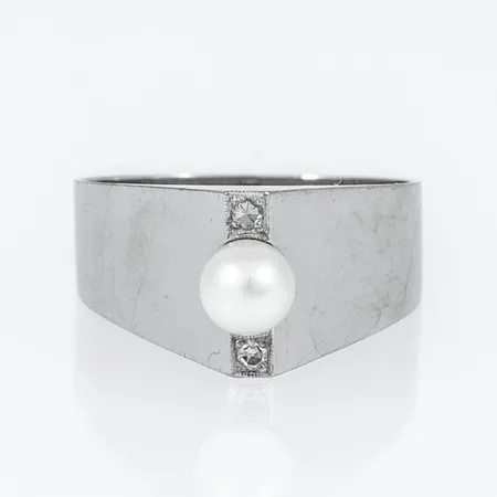 Ring i 18K vitguld med vit odlad pärla Ø 4,5 mm och 2 x 0,015ct 8/8 slipade diamanter. Den är i storlek 16¾, är 4 - 9,5 mm bred och väger 4,2g. Stenstorlek 0,03ct ingraverat. Stämplad S9 (1968), ALTON (Alton Guldvaru AB, Falköping), 18K och kattfot.