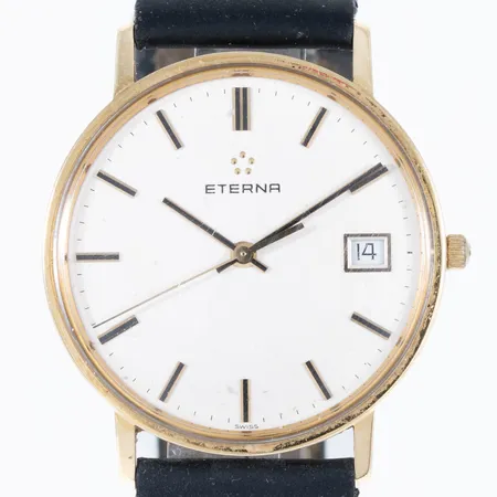 Herrur Eterna i 14K guld med svart (defekt) läderband. Boett Ø 33,5 mm, quartz, datum, svaga repor på glaset. Bruttovikt: 26,8g.
