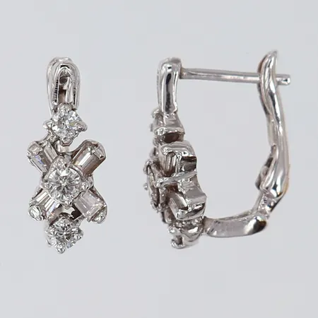 Ett par örhängen med briljantslipade diamanter 1 x 0,10ct, 2 x 0,04ct, samt baguette/trapetslipade diamanter, 15,5x6,5mm, glapp i fäste, felstämplade vitguld 14K.  Vikt: 2,8 g