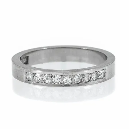 Ring i 18K vitguld med 9 x c:a 0,015ct 8/8 slipade diamanter. Den är i storlek 16½, är 3 mm bred och väger 3,7g. Stenstorlek 0,14ct ingraverat.