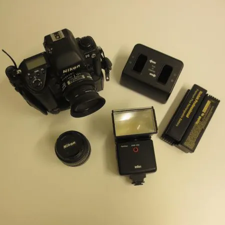 Kamerarunko Nikon F5 DCS 760, kaksi objektiivia:Nikon DX AF-S Nikkor 18-55mm, Nikon AF Nikkor 24mm 1:2.8, salama Braun VarioZoom 340M SCA ja laukku kuvaustarvikkeineen.