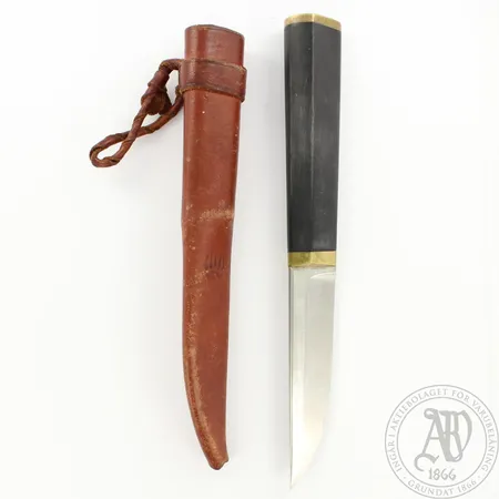 Puukko, Design Tapio Wirkkala, ruostumatonta terästä, nailonia ja messinkiä, nahkatuppi, terässä pieni lohkeama.